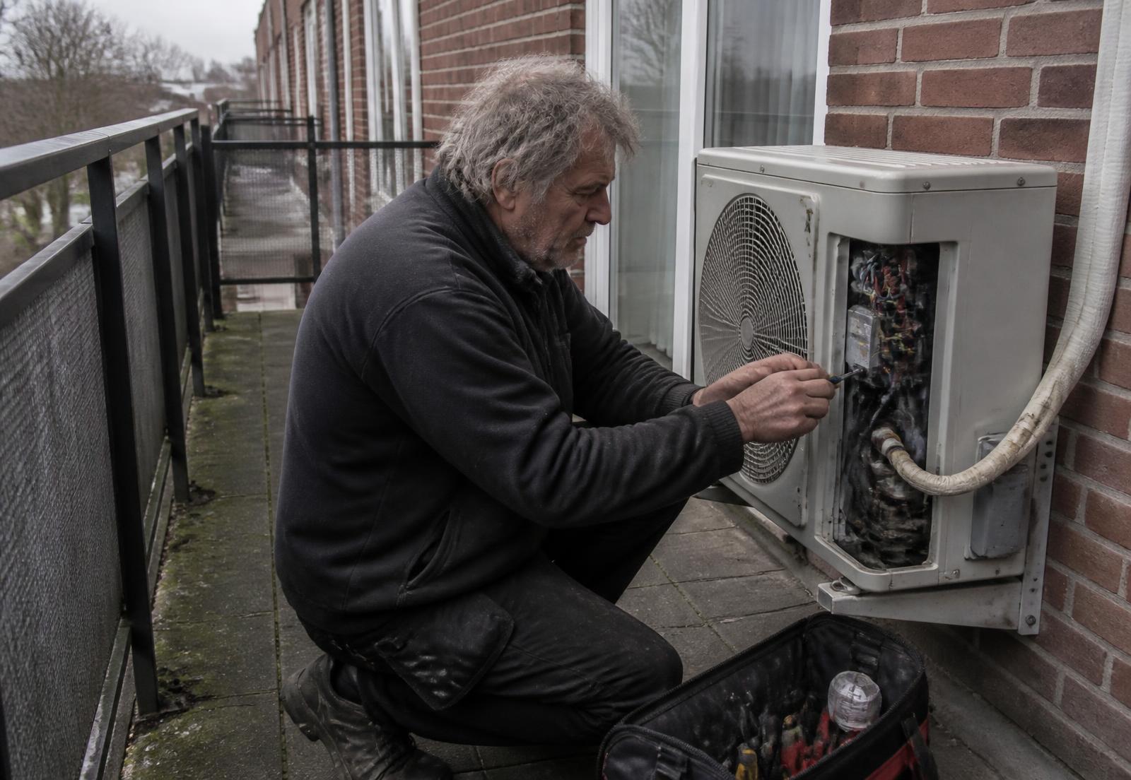 Monteur voert onderhoud uit aan een airco-buitenunit